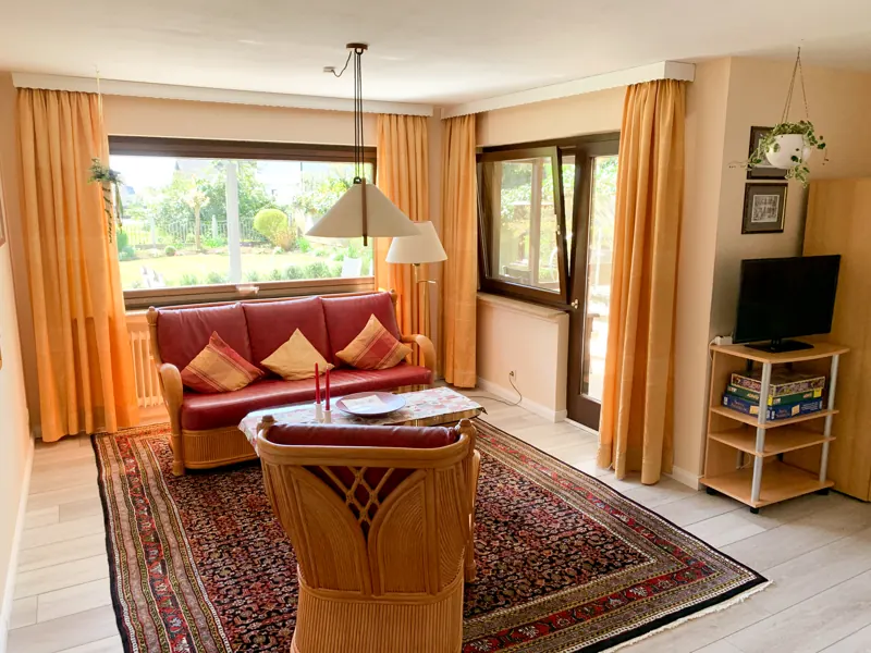 Wohnbereich mit rotem Sofa und Blick in den Garten